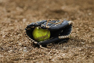 A yellow softball is shown in a glove on a field in this April 5, 2019 file photo. (AP/Aaron M. Sprecher)